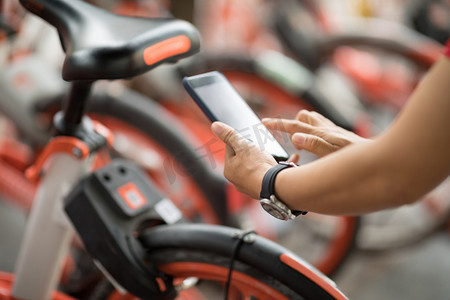Hands using smartphone for scanning the QR code of shared bike in city 