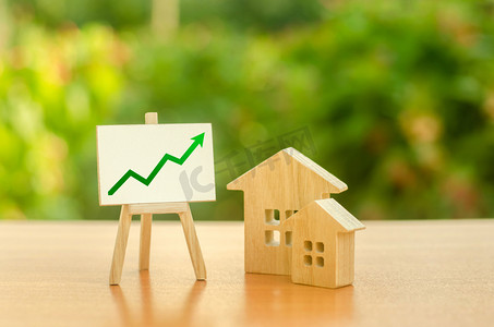 公寓出租摄影照片_两个木屋，用绿色向上的箭头站立。增加房地产的成本和流动性。有吸引力的投资。价格上涨或出租。公寓和公寓。销售率。供给和需求