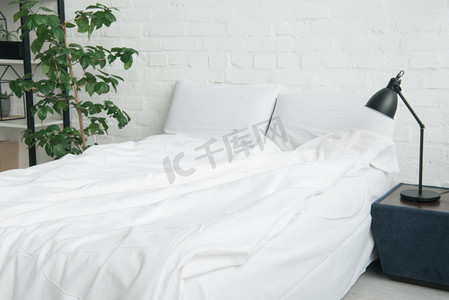 古人枕头摄影照片_床与白色毯子和枕头, 植物和灯在床头柜上