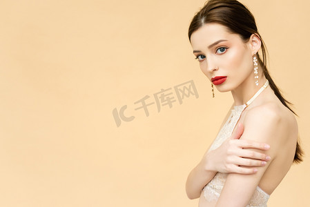 attractive young woman looking at camera isolated on beige with copy space