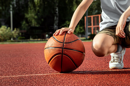 篮球场摄影照片_男孩手里拿着一个篮球特写镜头，背景是篮球场。运动生活方式的概念，训练，运动，休闲，度假.