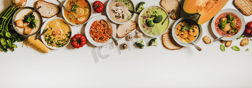 delicious摄影照片_Flat-lay of creamy homemade soup in plates with bread slices over white plain table background, top view, copy space. Autumn Winter creamy vegan soups, vegetarian food menu, comfort food concept