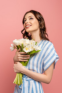 国际幸福日摄影照片_快乐的女孩抬起头，手里拿着一束粉红色的白郁金香