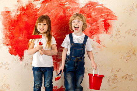 儿童画家。小艺术家手里拿着画笔, 墙上房间的墙纸上涂上了红色油漆.