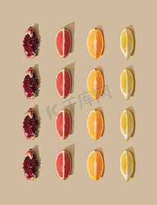 and摄影照片_Minimal nature pattern with grapefruit and orange with pomegranate and lemon slices on pastel sand background. Summer fruit concept. 