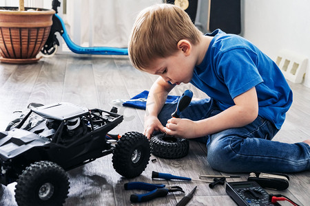 汽车造型: 小男孩在家修理一辆遥控汽车模型.