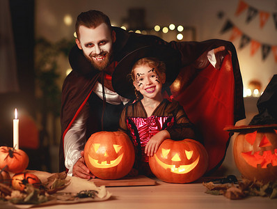鬼节巫婆摄影照片_幸福的家庭父亲和孩子的女儿在服装和化妆 