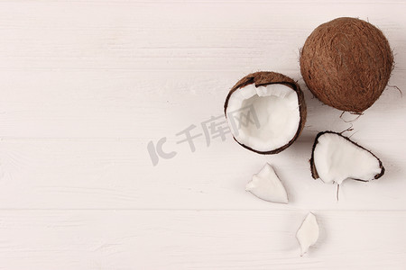 organic摄影照片_broken coconut on a colored background top view.