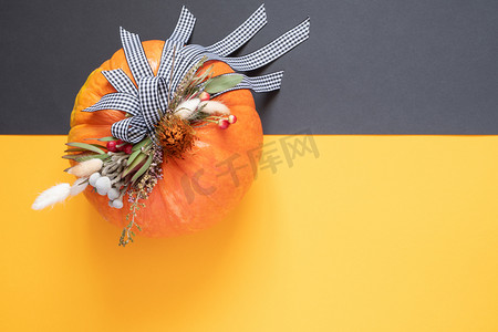 南瓜花摄影照片_万圣节或感恩节背景。秋天的组成南瓜与丝带和干花在双色调背景与复制空间.