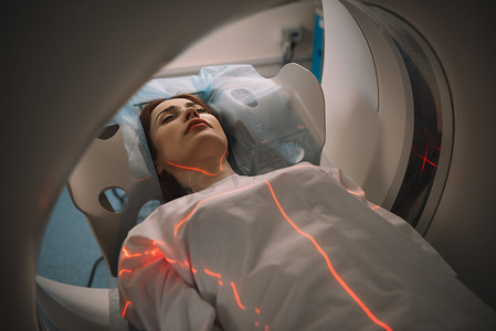 美丽的女人躺在CT扫描仪床上在医院进行断层扫描测试