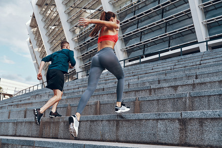 在基辅奥林匹克体育场，一群穿着运动服的年轻人在城市的楼梯上慢跑 
