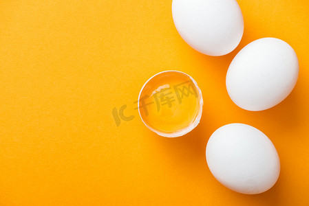 在白色整个鸡蛋中, 在明亮的橙色背景上, 用蛋黄砸碎的鸡蛋的顶部视图