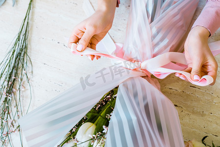 女性花商用丝带绑蝴蝶结的部分观点, 同时包裹花束 