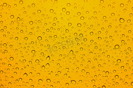 雨点落在汽车玻璃上。黄色背景。水滴图案