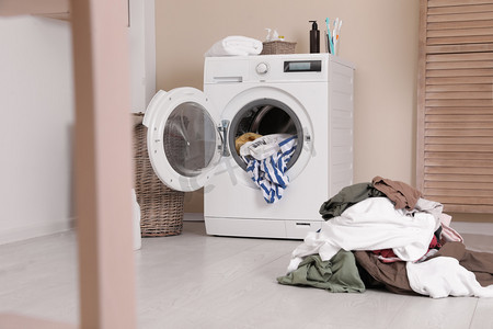 洗衣房摄影照片_洗衣房内部, 墙边有一堆脏衣服和洗衣机