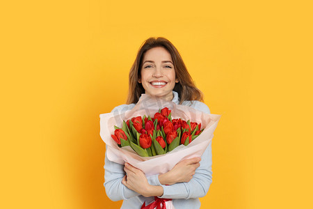 红郁金香花黄背景的快乐女人。三月八日庆祝活动
