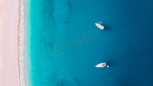 希腊密尔托斯，白色沙滩附近，有两艘游艇停靠在海面上