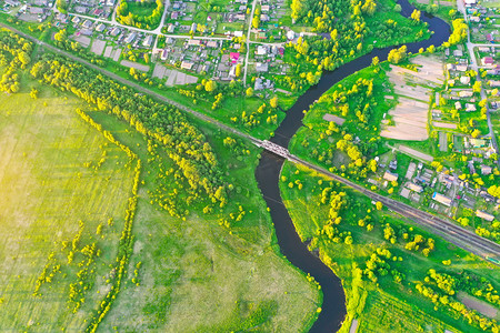小城镇间蜿蜒小河的空中景观，绿地草甸中的溪流，顶视图.