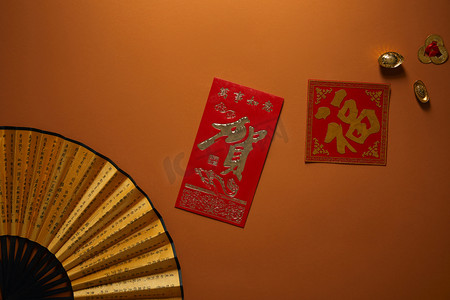 金黄标志摄影照片_风扇的顶视图与象形文字和金黄装饰在棕色背景, 中国新年构成