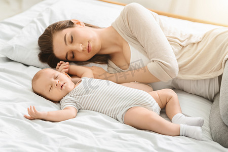 疲惫的母亲与新生儿的儿子睡觉，婴儿护理后精疲力竭
