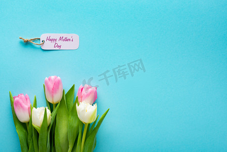带快乐母亲节字母的纸标签和带复制空间的蓝色表面郁金香的顶部视图