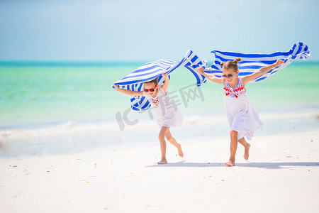 开心的小女孩用毛巾在热带海滩上运行
