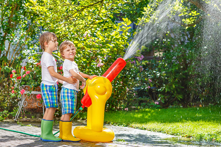 两个小孩子玩的橡胶软管和水在夏天