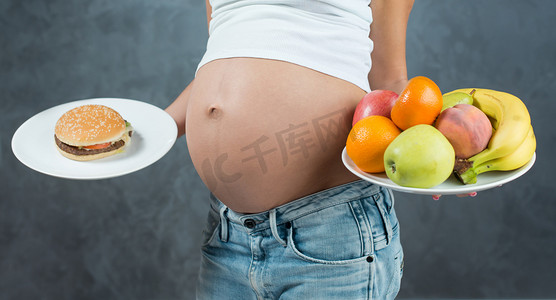 cute摄影照片_Close up of a cute pregnant belly tummy and healthy food. Pregna
