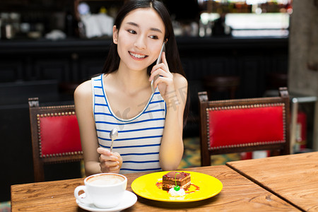 美丽的年轻女子坐在和吃蛋糕