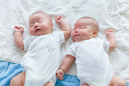 双胞胎婴儿摄影照片_躺在床上，睡的双胞胎