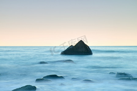 在海上的浪漫早晨。坚持从光滑水位的巨砾。与第一个炎热的太阳光线的粉红色 horozon.