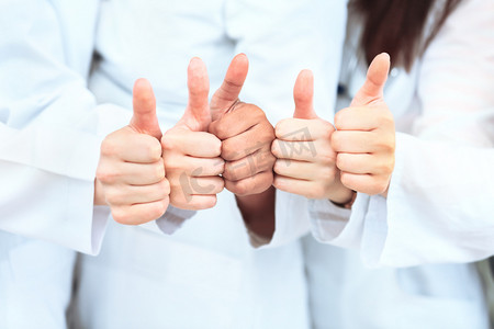 评价摄影照片_相信医生团队正站在诊所的行出现的拇指的肖像