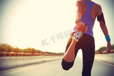 运动体育店摄影照片_伸展腿部的女跑步运动员