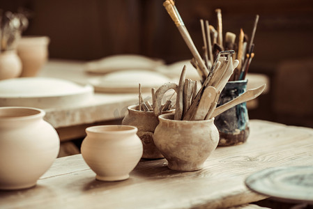 木工陶艺摄影照片_油漆刷与陶艺工具在桌上的碗的特写