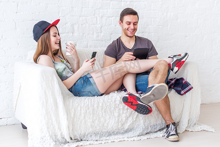 年轻的朋友们滑稽角色活跃的人愉快地在一起坐在沙发上发送消息聊天使用他们的智能手机在家里玩游戏概念社交媒体的应用程序