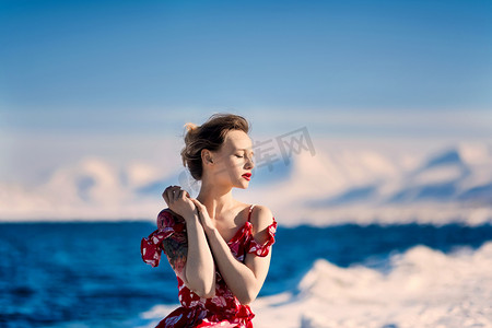 魔法故事摄影照片_女孩穿着红色山脉斯瓦尔巴群岛在斯匹次卑尔根市朗伊尔城，在阳光明媚的天气背景霜苗条美丽的金发女郎 