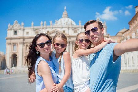 罗马人像摄影照片_快乐的年轻家庭在罗马梵蒂冈城的圣彼得大教堂教堂自拍。快乐旅行父母和孩子在意大利的欧洲度假自拍照片.