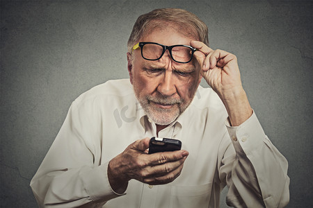 小男生演讲摄影照片_elderly man with glasses having trouble seeing cell phone