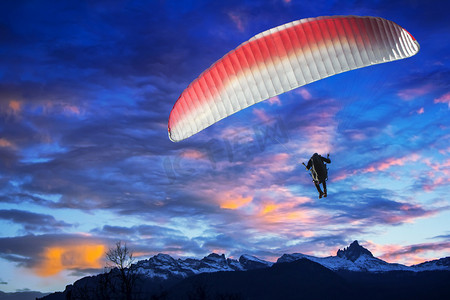 滑翔伞飞越山在冬日的太阳下山