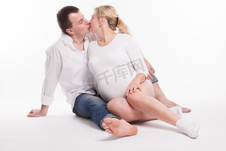 young dad in jeans and a white shirt and a pregnant woman in a w