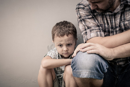 男孩郁闷摄影照片_悲伤的儿子抱着他的爸爸