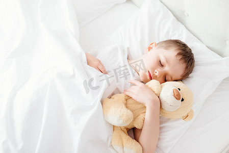 卧室枕头摄影照片_小男孩在床上睡觉