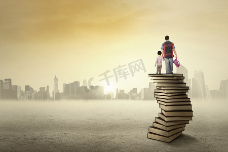 and摄影照片_Child and her dad standing on a pile of books
