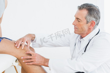 一个成熟的医生检查病人膝关节的侧视图