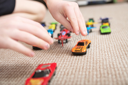 汽车和飞机摄影照片_男孩玩车集合在地毯上。孩子手玩。运输、 飞机、 飞机和直升机儿童玩具、 微缩模型。很多车的小男孩.