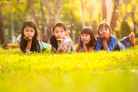 可爱的孩子在公园的绿草坪上尽情的泡沫