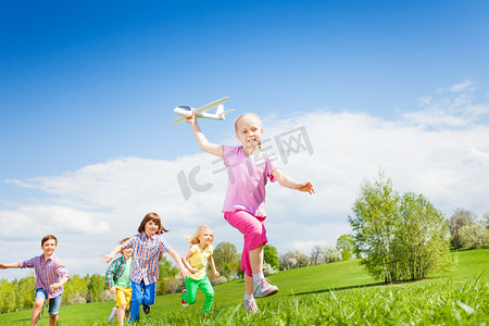 大通摄影照片_girl holds airplane with kids running