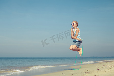 少女在夏天 vaca 的蓝色的大海岸边沙滩上跳跃
