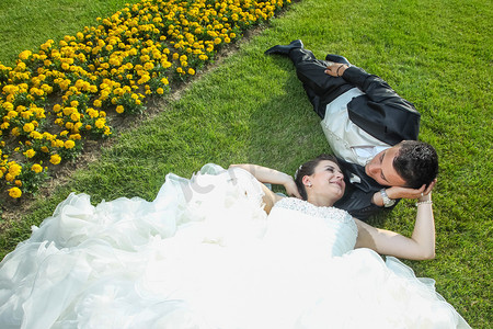 新娘和新郎躺在草坪上用鲜花