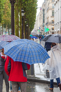 在雨天的巴黎香榭丽舍前进雨遮阳伞的人